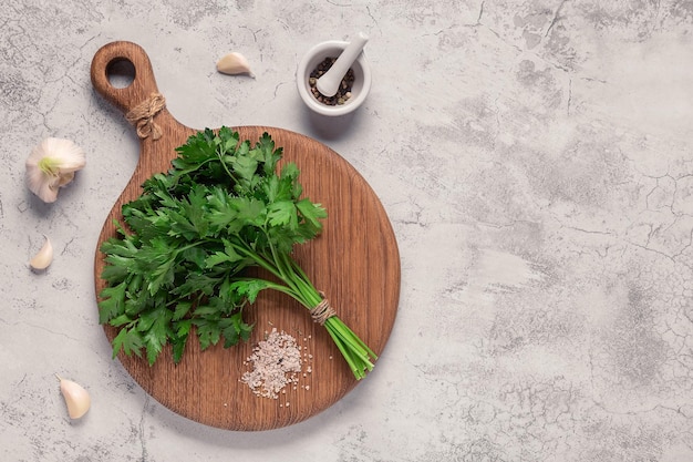 planche à découper, persil sur une table en béton, vue de dessus