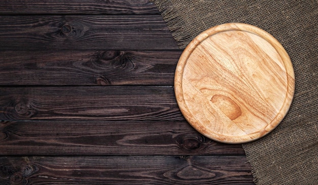 Planche à découper ronde sur table en bois foncé