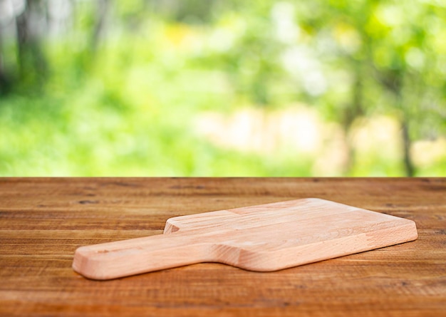 planche à découper sur une table en bois à l'extérieur avec fond de jardin