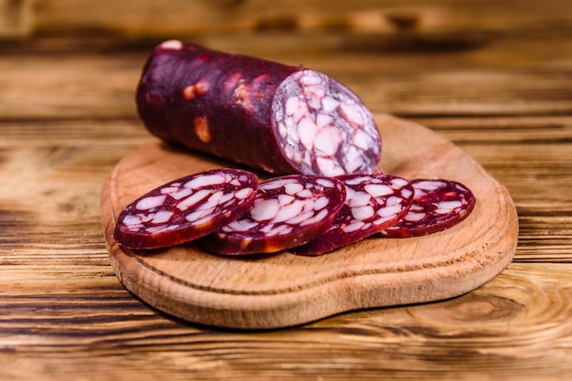 Planche à découper avec des tranches de saucisse de salami sur une table en bois rustique