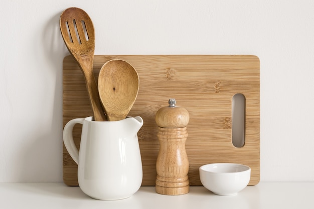 Planche à découper d'ustensiles de cuisine, cuillères et moulin à épices sur fond de mur de table.