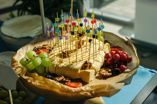 Planche avec de délicieux raisins au fromage et des noix sur du papier kraft Tableau rétroéclairé avec des produits