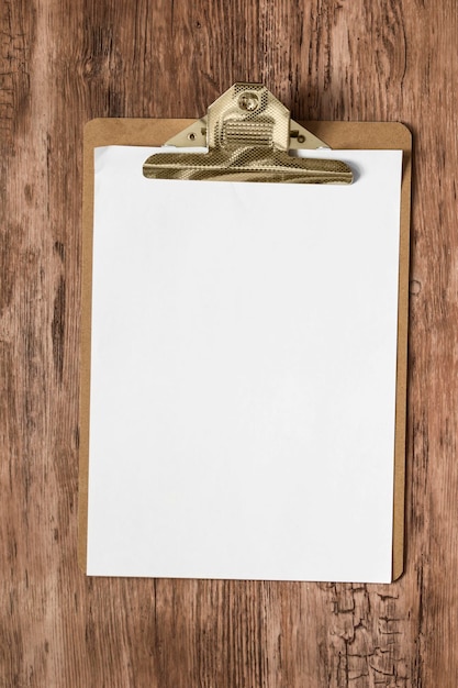 Photo planche à pince avec papier blanc vierge posé sur un fond en bois marron