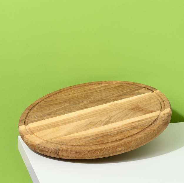 Planche de pizza de cuisine ronde en bois sur fond vert, ustensiles en lévitation, espace de copie