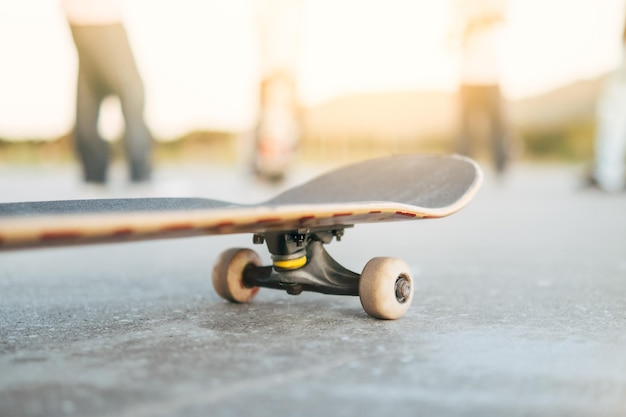 Planche à roulettes au premier plan avec des enfants patineurs qui parlent en arrière-plan Amis adolescents s'amusant à patiner Sport extrême amitié jeunesse concept selective focusxDxA