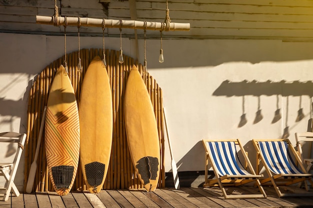 Photo planche de surf vintage en bois et clôture en bambou se dresse dans le sable