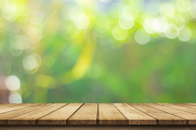 Plancher de bois avec des arbres flous de fond de parc naturel