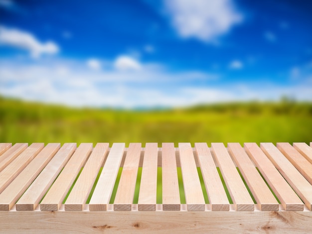 Plancher en bois avec champ vert et fond de ciel bleu