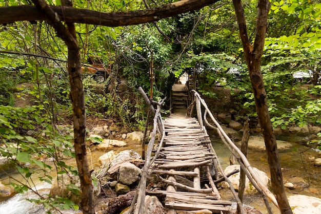 Plancher en bois d'un pont délabré au-dessus d'une rivière de montagne sur un sentier écologique dans une forêt de montagne d'été. photo de haute qualité