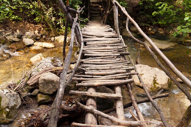 Plancher en bois d'un pont délabré au-dessus d'une rivière de montagne sur un sentier écologique dans une forêt de montagne d'été. photo de haute qualité