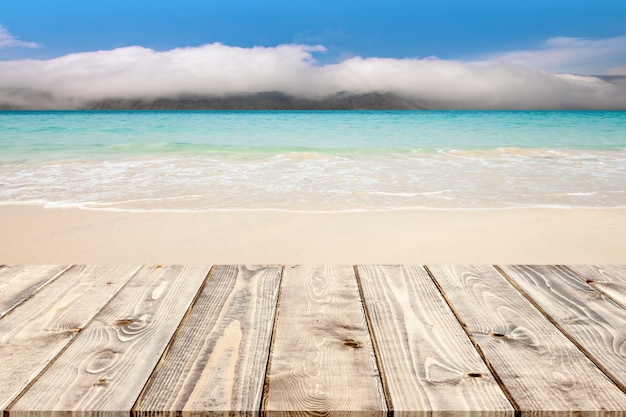 Plancher en bois vide sur la plage de sable blanc tropicale et fond de montagne brumeuse.