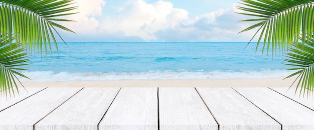 Planchers en bois et toile de fond de la mer Dessus de table en bois sur fond bleu flou de la mer et de la feuille de noix de coco en saison estivale