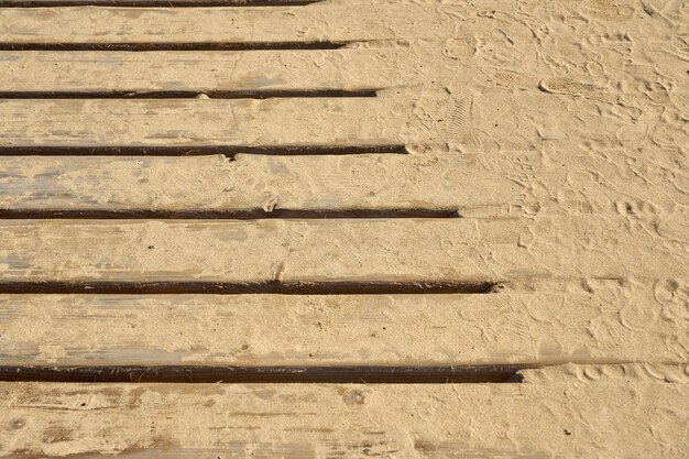 Les planches de bois du vieux pont sont recouvertes de sable en arrière-plan