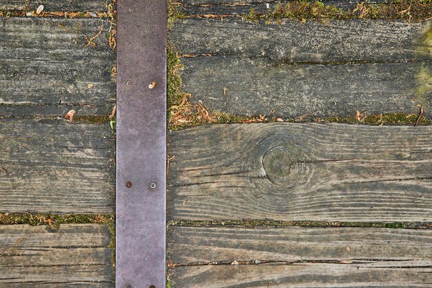 Planches de bois usées par les intempéries sur le chemin avec de la mousse poussant entre les lattes et la sangle métallique avec vis