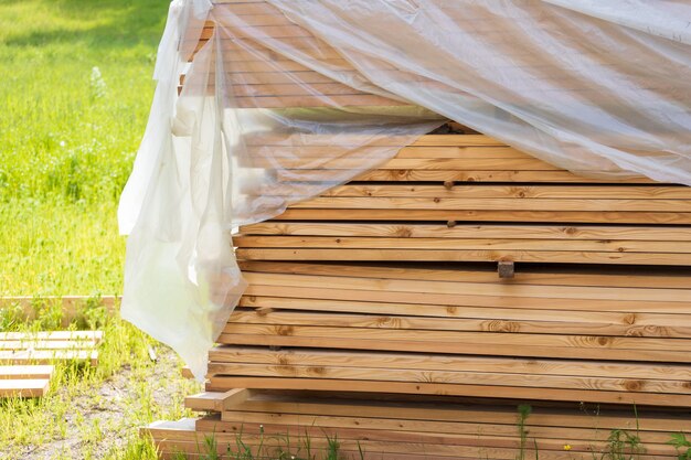 Les planches en tas recouvertes de polyéthylène se trouvent dans la nature. photo de haute qualité