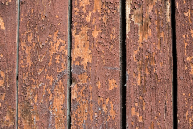 Planches verticales en bois recouvertes de peinture rouge écaillée.