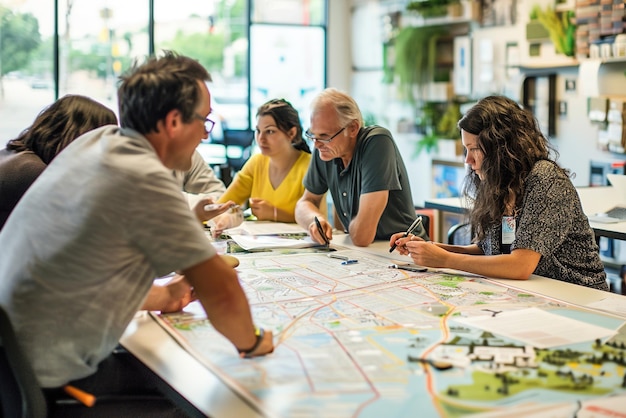 Planificateurs de mobilité urbaine brainstorming dans un bureau d'aménagement urbain cartographiant les réseaux de transport vélo