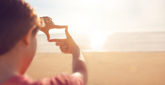 Planification future, Gros plan des mains de femme faisant le geste de cadre avec le lever du soleil sur la mer été