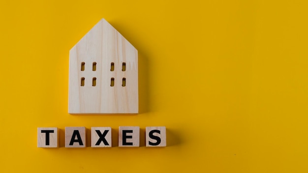 Planification d'investissement de concept de taxe foncièreBlocs de bois avec le mot TAXES et une maison sur fond jaune