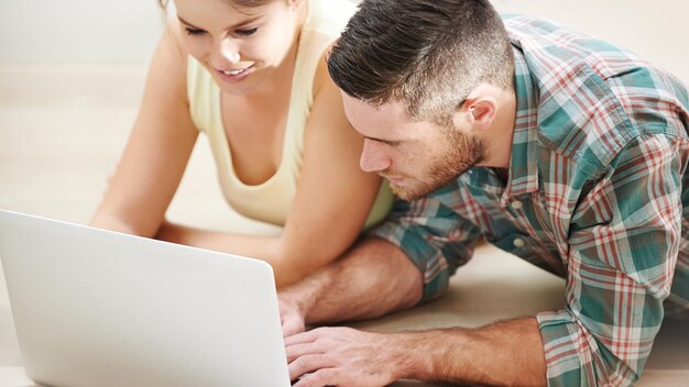 Planification d'une nouvelle maison ou un couple sur un ordinateur portable pour la recherche lecture d'un article en ligne sur le site de design d'intérieur option de location de plancher ou les gens tapant sur la technologie pour la rénovation choix hypothèque ou prêt