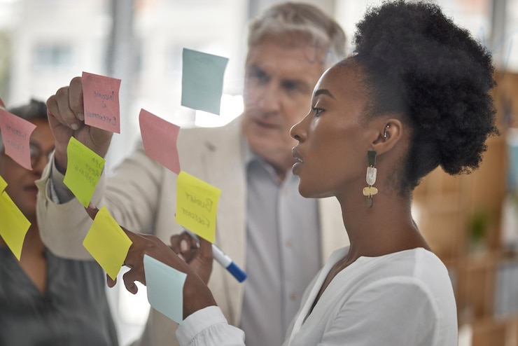 Photo planification de réunion et verre avec une femme noire menant une présentation dans une salle de réunion pour la stratégie de l'entreprise présentation de travail d'équipe et notes autocollantes dans un bureau avec une employée parlant au personnel