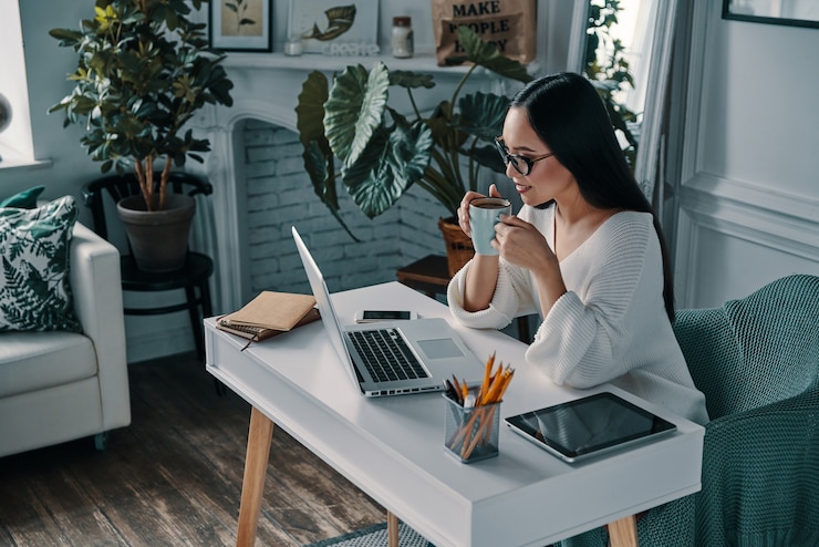 Photo planifier une autre étape. vue de dessus de la belle jeune femme travaillant à l'aide d'un ordinateur et souriante assise au bureau à domicile