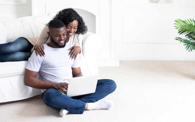 Planifier des vacances ensemble. Jeune famille afro-américaine utilisant un ordinateur portable à la maison, réservant un voyage commun, espace de copie