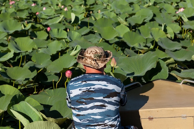 Plantation De Fleurs De Lotus. L'homme En Bateau étudie, Observe Et Photographie Les Boutons Floraux.