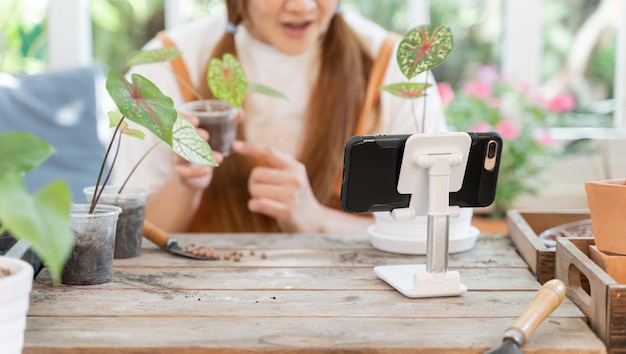 Planter des arbres au jardin botanique et utiliser un smartphone pour vendre en ligne. Mode de vie de la femme asiatique au printemps.