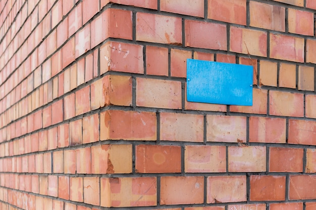 Une plaque bleue vierge est vissée à un mur de briques. Un signe au coin d'un immeuble en brique.