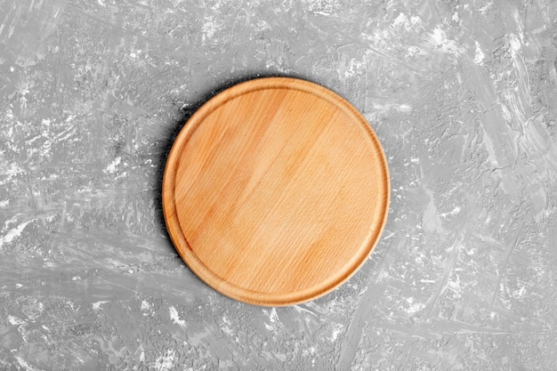 Photo plaque de bois ronde vide sur table sur fond de mur de ciment gris pour le montage de l'affichage du produit