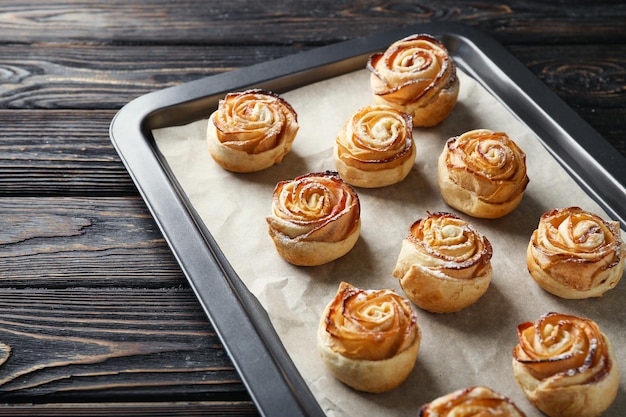 Plaque de cuisson avec pommes roses à partir de pâte feuilletée sur fond de bois