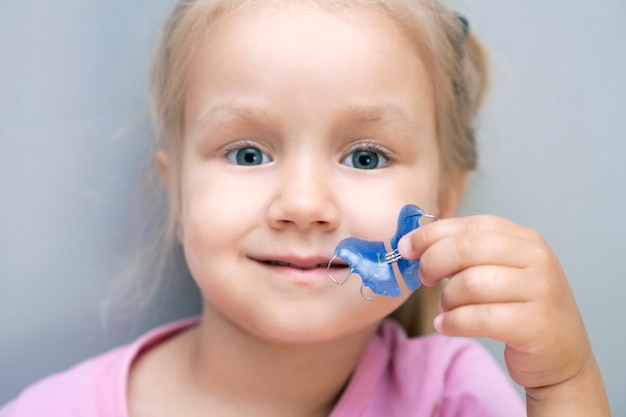 Plaque dentaire. Expansion de la mâchoire chez un enfant. Une assiette au paradis. Il n'y a pas assez de place pour les molaires. Fille heureuse tenant une plaque orthodontique dans ses mains