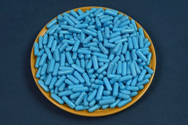 Plaque jaune pleine de capsules de médicaments bleues représentant une surdose de drogue