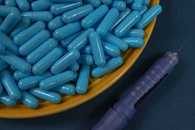 Plaque jaune pleine de capsules de médicaments bleus représentant une surdose de médicament