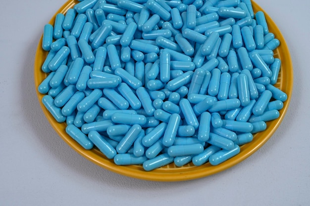 Plaque jaune pleine de capsules de médicaments bleus représentant une surdose de médicament