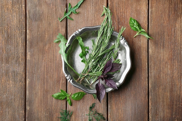 Plaque de métal avec basilic romarin et roquette sur fond de bois