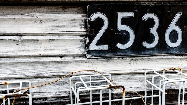 Photo plaque de métal avec numéro sur un mur en bois blanc