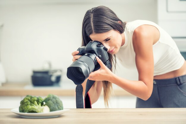 Plaque de photographie professionnelle de femme avec du brocoli. Photographe culinaire travaillant dans un studio de cuisine.