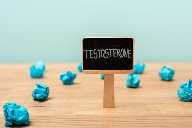 Plaque signalétique avec lettrage de testostérone près de papier froissé sur une surface en bois isolée sur bleu