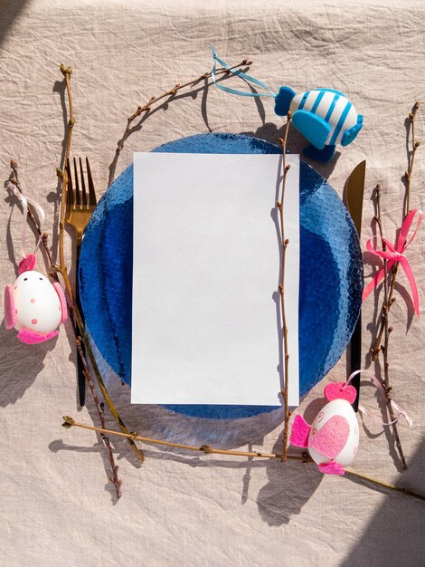 Photo plaque de table de pâques avec feuille de papier blanc maquette d'œufs branches drap de table en lin menu festif