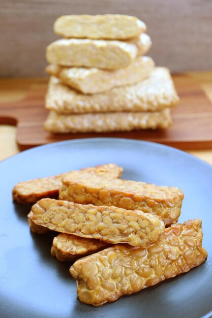 Plaque de Tempeh frit à la poêle avec une pile de crème crue en arrière-plan