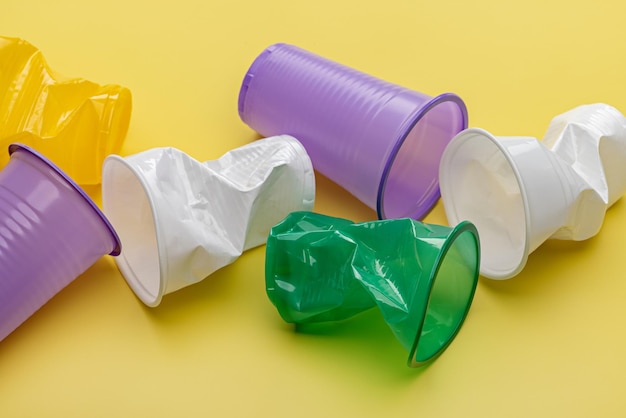 Plastique usagé. Gobelets jetables multicolores sur fond jaune. Le concept d'écologie.