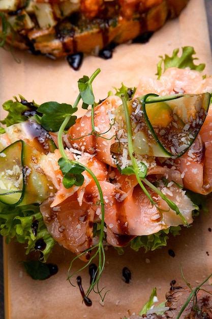 Un plat de 3 tapas différentes farcies de viande de poisson et de divers microverts servis sur une planche sur fond sombre