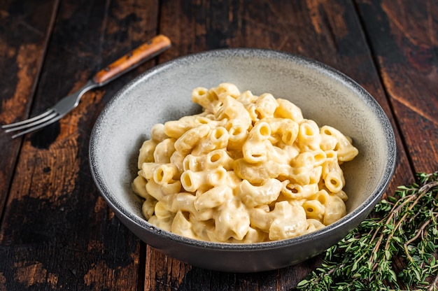 Plat américain Macaroni au fromage et pâtes macaroni au Cheddar. Fond en bois sombre. Vue de dessus.