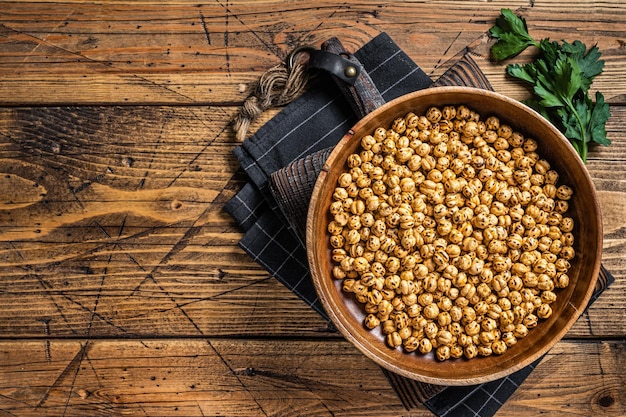 Plat arabe Pois chiches rôtis dans une assiette en bois. Fond en bois. Vue de dessus. Copiez l'espace.