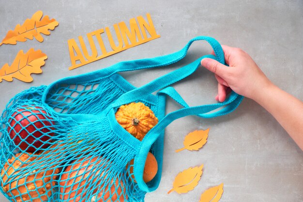 Plat à l'automne avec un sac à cordes turquoise avec des citrouilles orange, le haut vie sur pierre grise