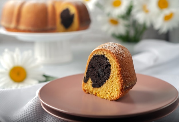 Sur un plat blanc, un cupcake rond, rond avec un trou, saupoudré de sucre en poudre