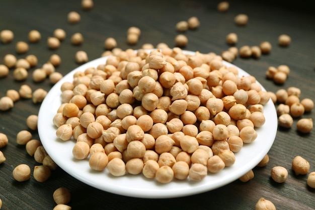 Un plat blanc rempli de pois chiches séchés avec des noyaux éparpillés