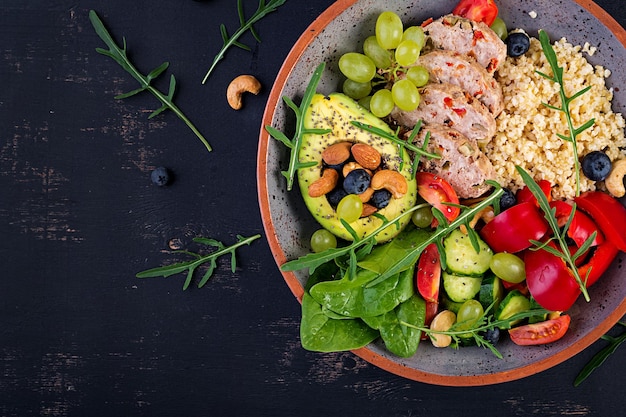 Plat de bol de Bouddha avec pain de viande bulgur avocado poivre sucré tomate concombre baies et noix Détox et superaliments sains concept de bol vue aérienne à plat